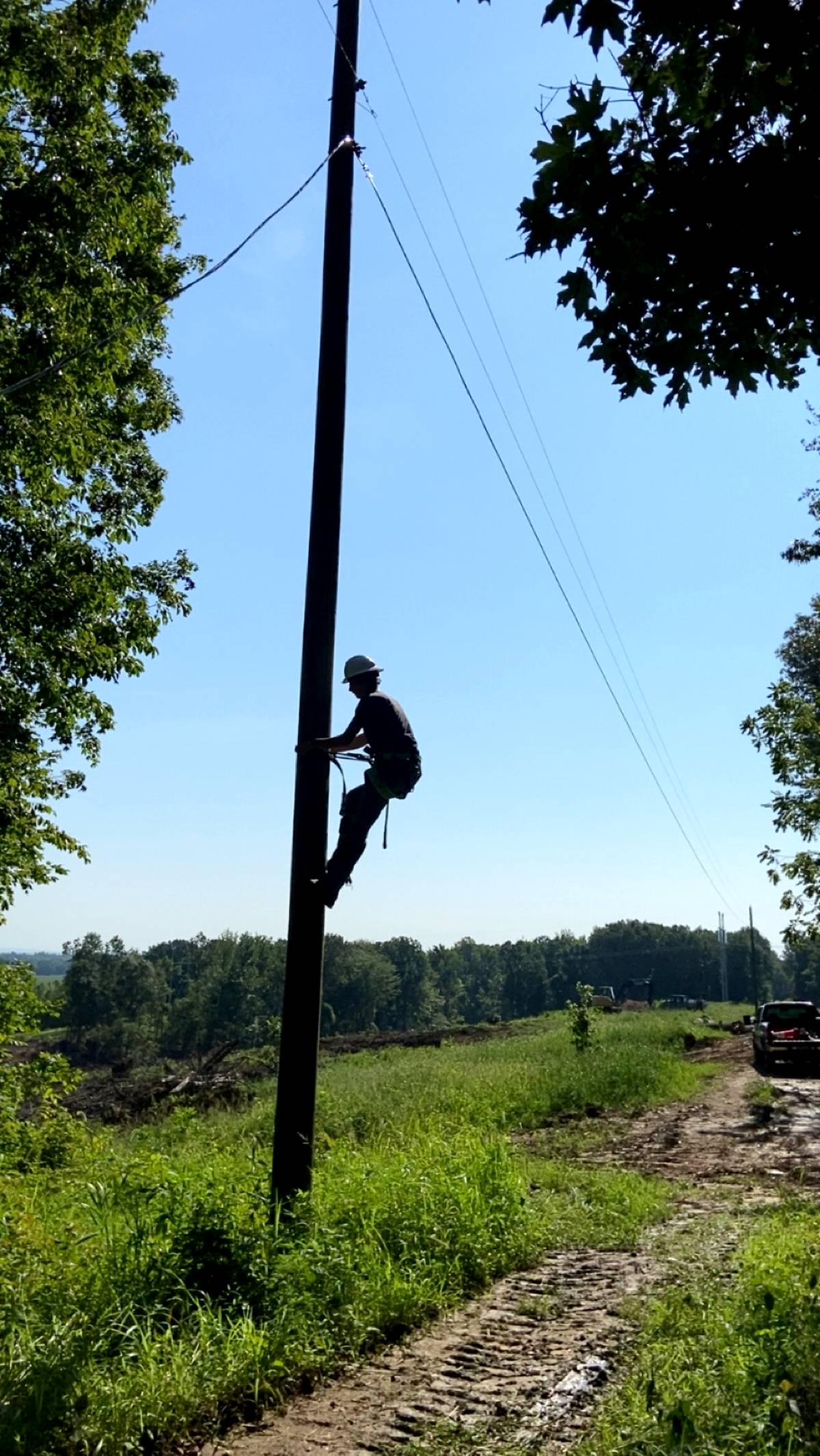 Bucket truck and crew setting lines in rural area